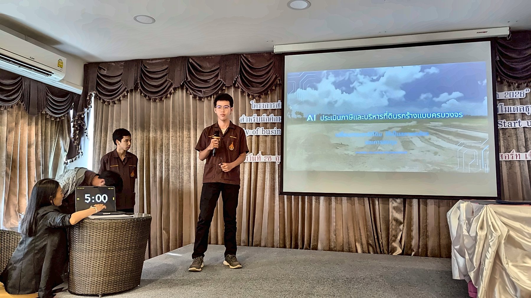 Our team pitching 'AI land tax assessment and vacant-land management' on stage, with the 5-minute timer running